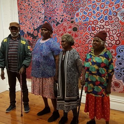 Artists from the Spinifex Arts Project in Pitjantjatjara lands in Western Australia standing in front of a collaborative map of country.